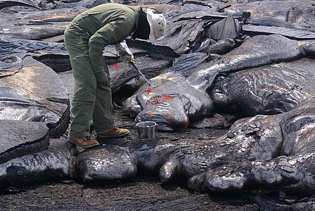 man in green jumpsuit taking lava sample thumbnail