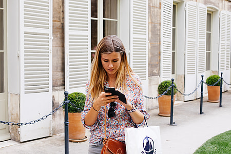 woman walking while surfing on phone during daytime thumbnail