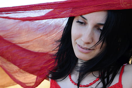 woman smiling under red textile thumbnail
