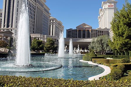 low angle photography of water fountain beside white building during daytime thumbnail