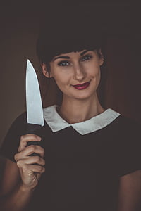 woman in black and white collared blouse smiling and holding knife thumbnail