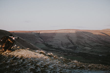 person taking picture of brown mountains thumbnail