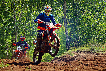 two riders racing at motocross field surrounded by trees during daytime thumbnail