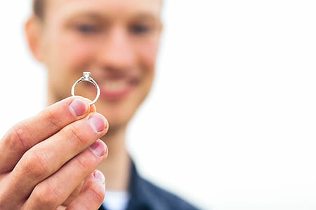 selective focus photography of man holding silver-colored ring thumbnail