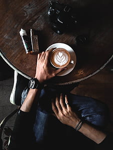 person sitting holding espresso coffee filled cup on table thumbnail