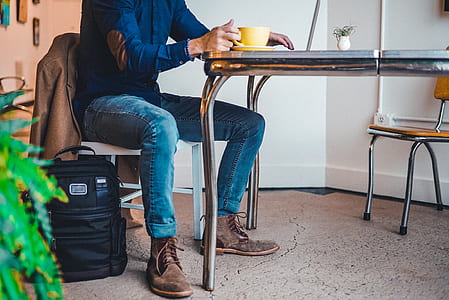 man wearing blue dress shirt and blue denim fitted jeans outfit sitting on white chair thumbnail