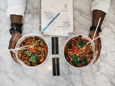 two hand holding white bowl with noddles thumbnail
