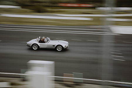 time lapse photo of white convertible coupe on road thumbnail