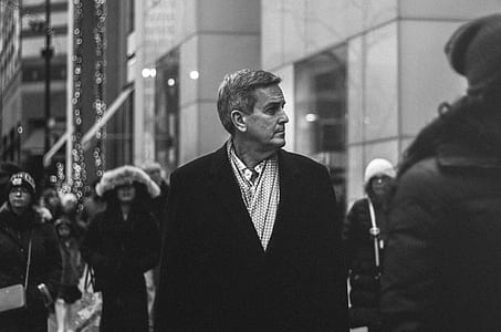 grayscale photo of man walking in crowd thumbnail