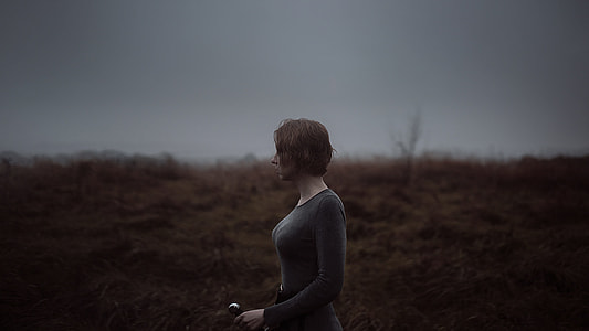 woman in grey crew-neck long-sleeved shirt standing of beige grass field thumbnail