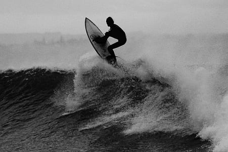 grayscale photo of man riding surfboard thumbnail