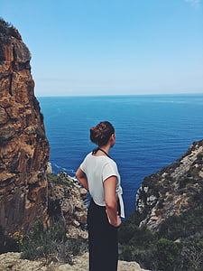 woman in white shirt standing beside cliff thumbnail