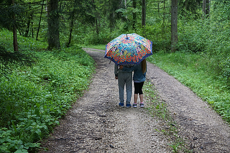 two person walking on road holding floral umbrella beside green trees thumbnail