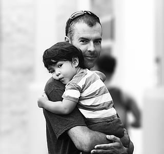 grayscale photography of man carrying baby thumbnail