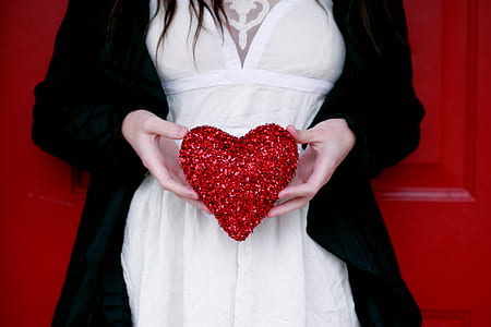 woman holding heart shape decor leaning on red door thumbnail