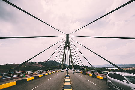 vehicles passing on gray suspension bridge at daytime thumbnail