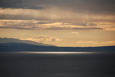 sea and mountains under cloudy sky at daytime thumbnail