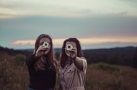 two women holding white flowers thumbnail