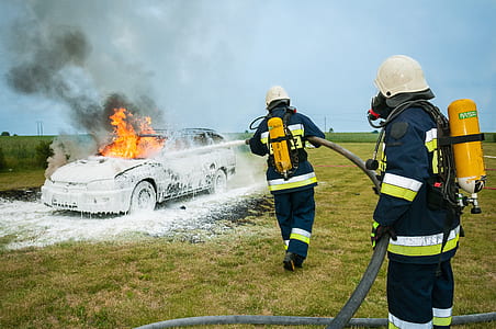 two firefighters fighting fire on grey station wagon on field during daytime thumbnail