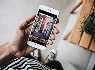 person hand holding iPhone displaying houses thumbnail