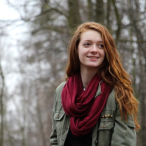 Woman in Green Zip Up Cargo Jacket and Red Scarf Smiling Sideways thumbnail