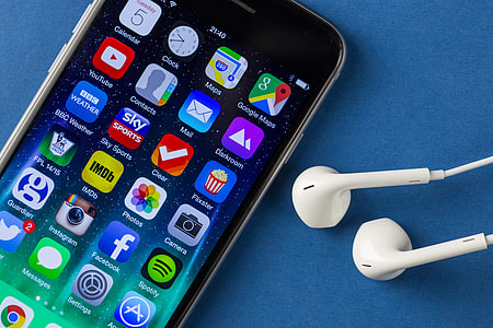 Close-up shot of the iPhone 6 mobile smartphone and earphones on a plain blue background thumbnail