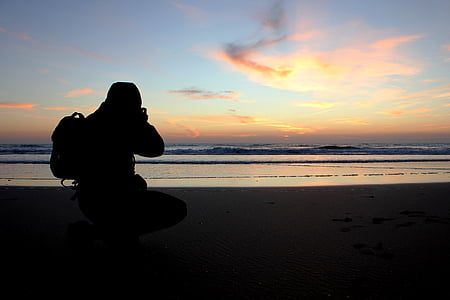 man capturing sunset on beach shore thumbnail
