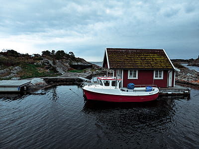 White and Red Powerboat Park Beside Red House thumbnail
