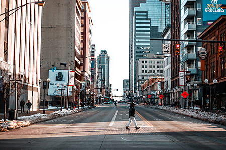 man walking on road surrounded by buildings thumbnail