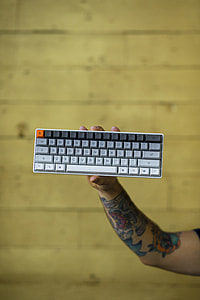 person holding grey and black computer wireless keyboard thumbnail