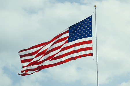 rising USA flag under white cloudy sky thumbnail