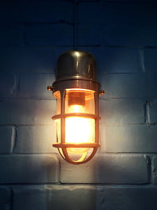 gray turned-on sconce lamp with cage on white wall thumbnail
