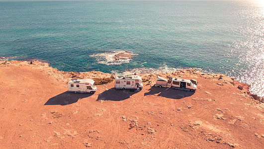 three white RV near on seashore during daytime thumbnail