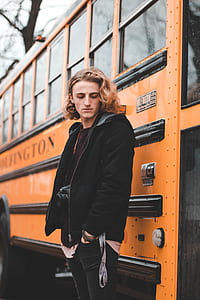 man standing near orange bus thumbnail