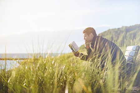 man sitting on bench reading book thumbnail