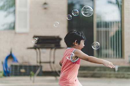 selective focus photography of boy chasing bubbles thumbnail