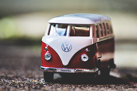 white and red Volkswagen T1 scale model on gray dirt selective focus photography thumbnail