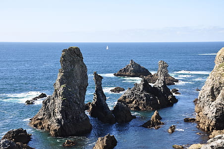 several gray boulders surrounded by body of water thumbnail