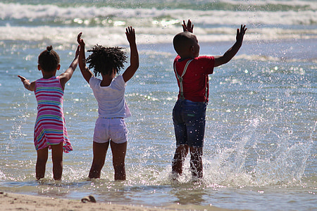 three kids playing on grey body of water during daytime thumbnail