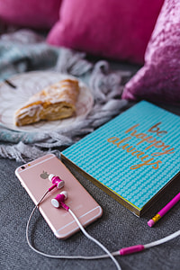 Blue notebook with a pink iPhone, headphones and a sweet bun thumbnail