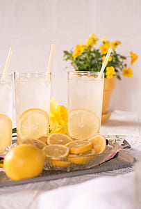 three filled pint glasses with sliced lemons near flowers thumbnail