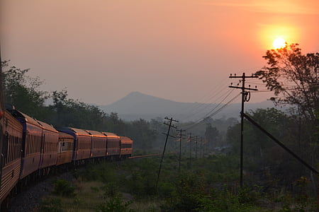 gray locomotive train passing near electric post during golden hour thumbnail
