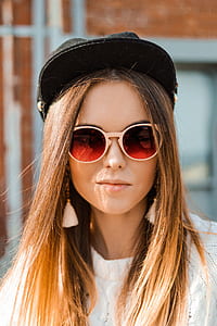 woman wearing red tinted sunglasses and black hat outdoors thumbnail
