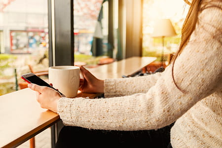 Young girl uses her smartphone at cafe thumbnail