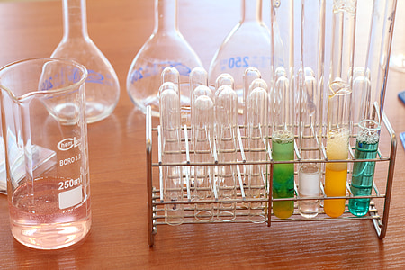 clear glass test tubes set with stainless steel rack near measuring cup thumbnail