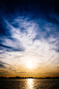 silhouette photography of land near sea under white clouds thumbnail