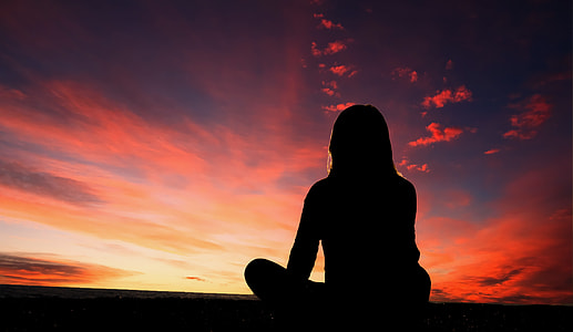 silhouette of woman looking at sun during orange sunset thumbnail