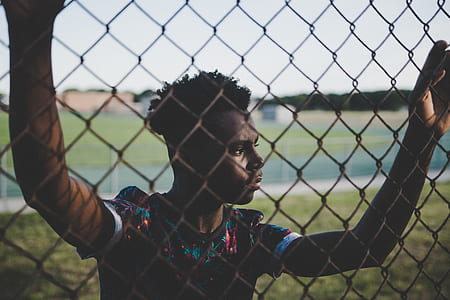 man standing while holding chain link during daytime thumbnail