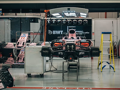 black and pink F1 car beside yellow A-frame ladder thumbnail