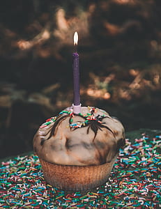 cupcake with rainbow sprinkles topped with lighted candle thumbnail